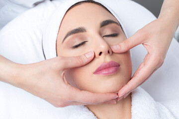 Fototapeta na wymiar Young woman doing facial massage in a beauty salon.