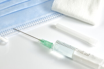 Prepared syringe with needle, sterile gauze, and surgical mask.