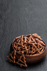 Christmas tree shapes pretzel in wooden bowl on black stone background