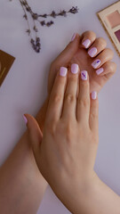 Beautiful female fingernails with purple nails near lavander flowers and cosmetics elements. Perfect manicure