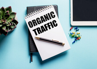 On a light blue background, there is a potted plant, a tablet and a weekly with the text ORGANIC TRAFFIC