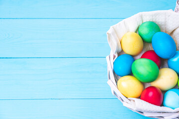 basket with colorful Easter eggs on a blue wooden background, selective focus, tinted image