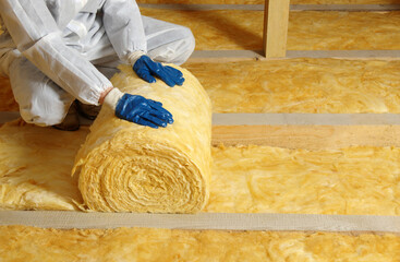 Man installing thermal insulation layer under the roof