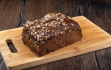 Fototapeta na wymiar Whole loaf of rye bread with sunflower seeds on a wooden cutting board.