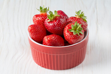 Red bowl with strawberries on a old wooden background