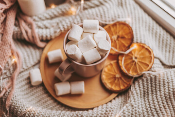 pink cup with marshmallows on a wooden tray and citrus slices