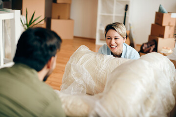 Obraz premium Cheerful woman having fun with her husband while moving into new apartment.