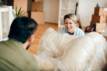 Cheerful woman having fun with her husband while moving into new apartment.