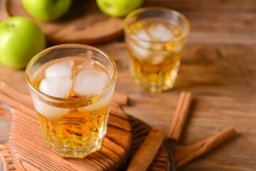 Tasty apple drink with cinnamon in glasses on wooden background