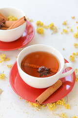 Tasty herbal tea with cinnamon and anise in cups on light background