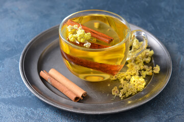 Tasty herbal tea with cinnamon in cup on color background