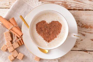 Tasty coffee with cinnamon in cup on wooden background