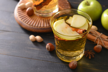 Tasty apple drink with cinnamon in glass on dark background