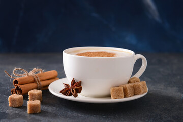 Tasty coffee with cinnamon in cup on dark background