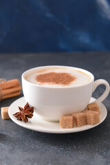 Tasty coffee with cinnamon in cup on dark background
