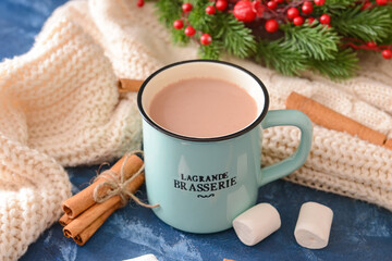 Tasty hot cocoa with cinnamon and marshmallow in cup on color background
