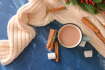 Tasty hot cocoa with cinnamon and marshmallow in cup on color background