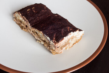 A serving of tiramisu cake with cream and brandy. Sweets with cocoa and natural coffee.