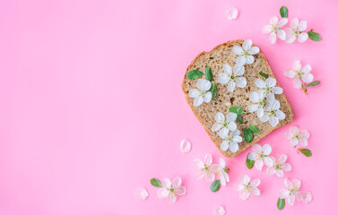 piece of bread with flowers on a pink background. Spring background. Space for the text.