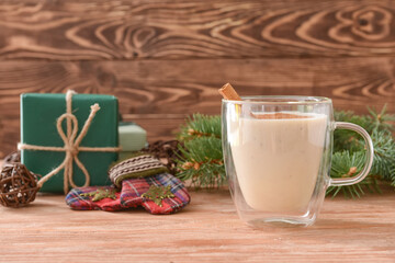 Tasty milkshake with cinnamon in cup on wooden background