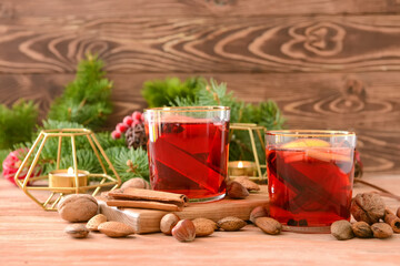 Tasty mulled wine with cinnamon and nuts in glasses on wooden background