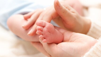 Obraz na płótnie Canvas Closeup shot of little newborn baby feet in gentle mothers hands. Concept of family happiness and loving parents with little children