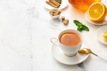 Cup of hot tea with lemon and mint on light background