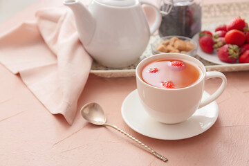 Cup of hot strawberry tea on color background