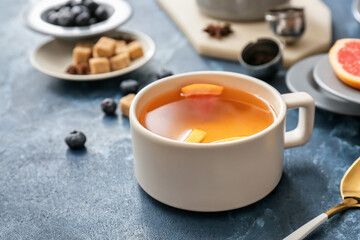 Cup of hot tea with grapefruit on color background