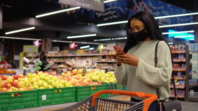 Girl in a mask talking on the phone in the supermarket. Shopping concept