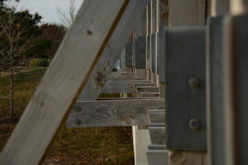 Close up look at part of the wood beams of a bridge forming triangles with their nuts and bolts