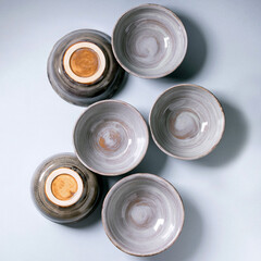 Set of empty craft ceramic bowls cover by grey texture glaze over gray background. Flat lay