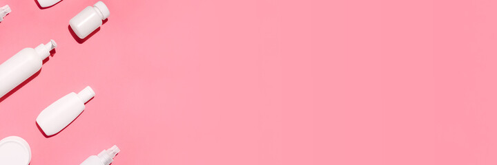 Banner with white cosmetic bottles mockup on pink background. Tubes, dispensers and jars. Branding identity concept. Flat lay with copy space