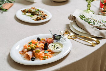 Seafood platter with salmon slice, black caviar, decorated with olive on white plate.