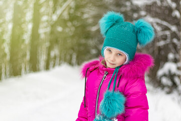 natural light. a girl in a red jacket and a green hat is surrounded by a lot of snow. He looks at us. Soft focus.