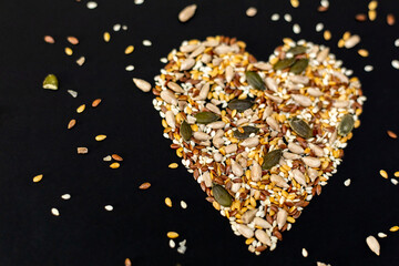 Heart-shaped seed mix on a black background.