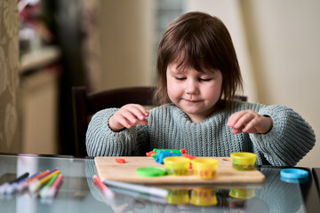  A little girl is passionate about modeling from plasticine. Selective focus. Copy space.