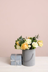 Beautiful flowers and gift on table against color background