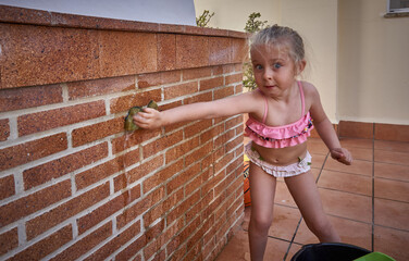 Retrato de ni&ntilde;a rubia jugando alegremente con una esponja y agua