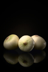 White onions on a black background reflected on the base. Gastronomic ingredient from all kitchens.