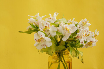 Florero amarillo con ramo de flores blancas sobre una mesa de mármol y fondo de color amarillo. concepto decoración de interiores