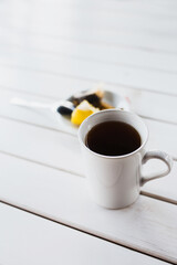 Hot black tea in a white cup with honey and lemon