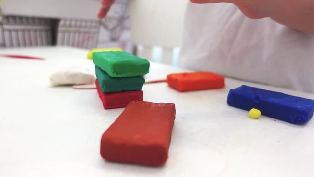 Close-up of child's hands sculping and building from plasticine..Slow-motion video with children's creativity. Home activity for children's development on white background