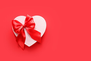 Wooden heart and red bow on color background