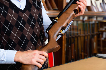 Closeup of modern sporting air PCP pump-action rifle in hands of gun shop seller.