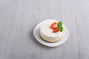 Top view of classic cheesecake garnished with strawberries and mint.