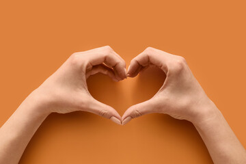 Hands making heart on color background