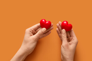 Hands with red hearts on color background