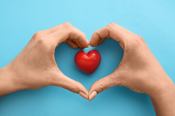 Hands with red heart on color background