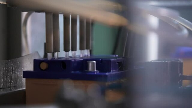 In an industrial battery manufacturing plant. Pouring electrolyte into a car battery.